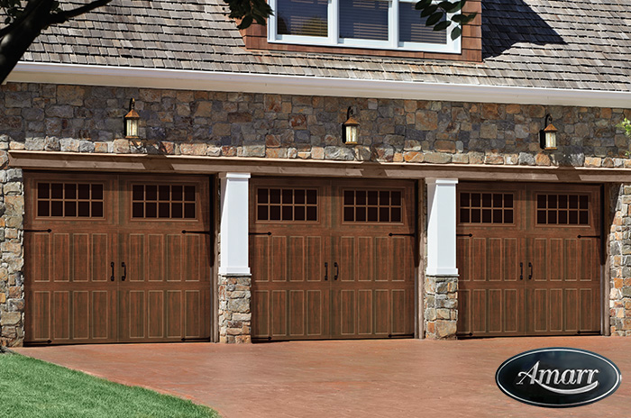 Stone home with custom wood-look carriage garage doors installed by Pioneer